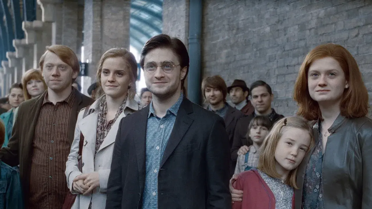 Harry Potter, z charakterystyczną blizną, stoi w tłumie na dworcu. Obok niego Hermiona i Ron.