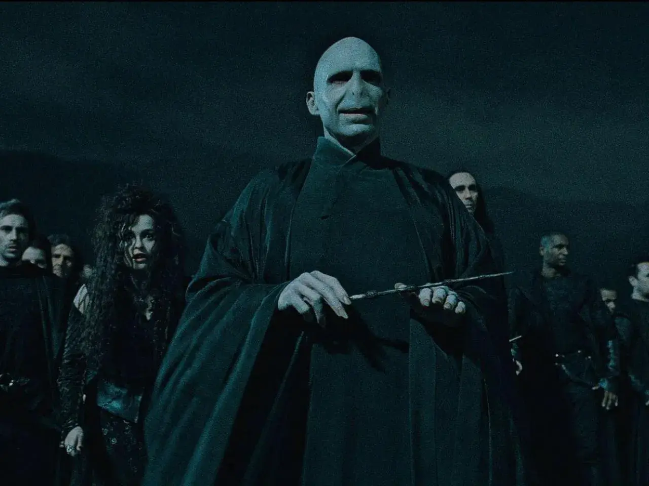 Lord Voldemort, jak miał wyglądać, w otoczeniu śmierciożerców, z różdżką w dłoni.
